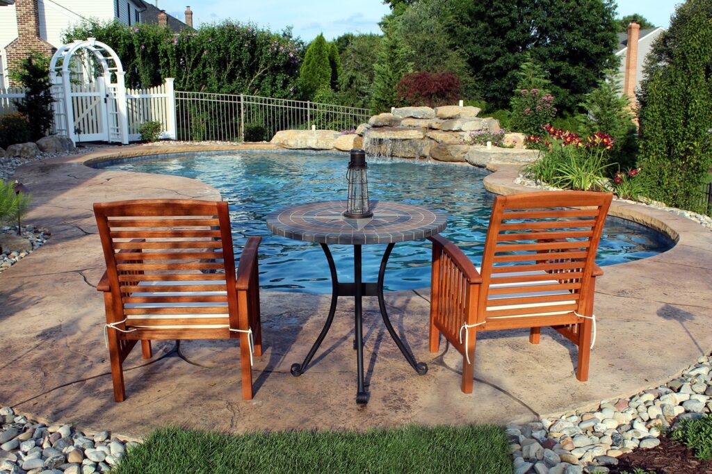 A custom made backyard pool in Lehigh Valley, with two chairs nearby.